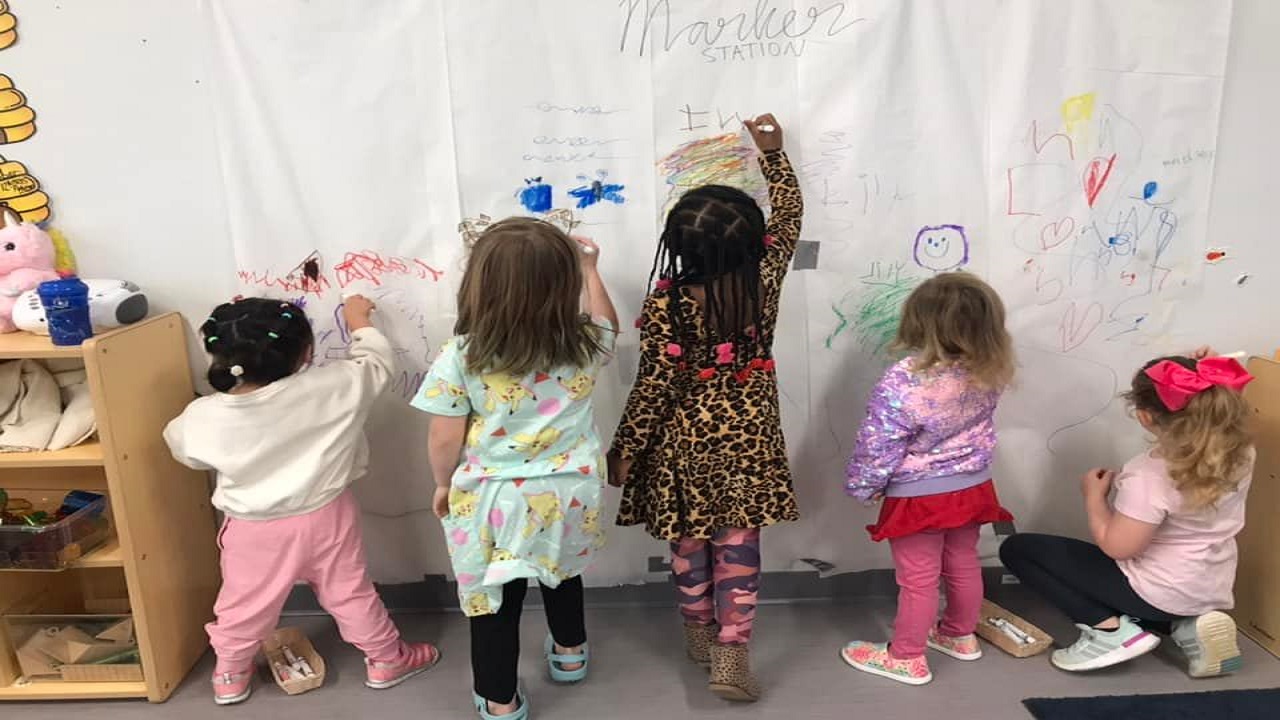 children coloring on a wall covered with paper
